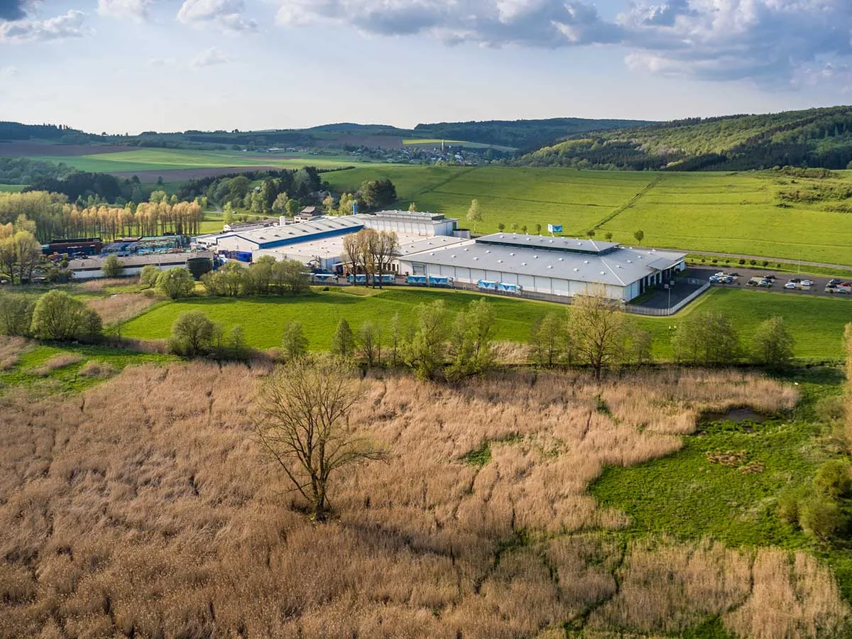 Luftbild des Abfüllbetriebs der Nürburg Quelle in Dreis-Brück, ringsum Wiesen und Wald der Vulkaneifel